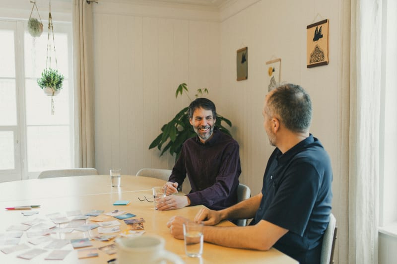 Deux hommes riant autour de la table de réunion — partie de cartes